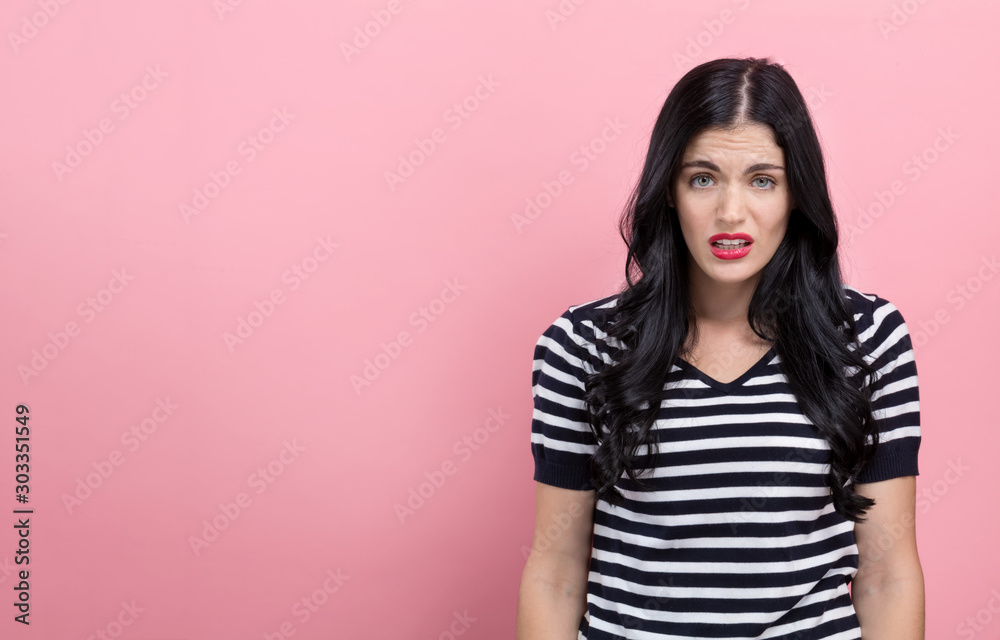 Disgusted face expression with young woman on a pink background Disgusted face expression with young woman on a pink background