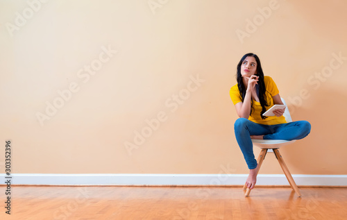 Young woman using her tablet sitting in a chair