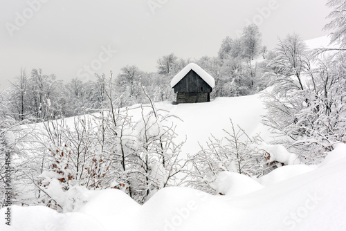 Minimalistic winter landscape with wooden house in snowy mountains. Cloudy weater, landscape photography © Ivan Kmit