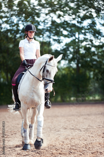 Young pretty teenage girl equestrian practicing horseback riding on manege © AnnaElizabeth