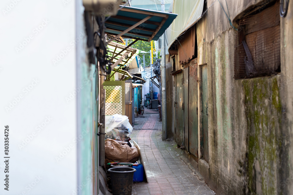 Narrow alley in the slums. Poor neighborhood. Marginal living standards. Garbage, old things and bicycles in the area where not rich people live Narrow alley in the slums. Poor neighborhood. Marginal living standards. Garbage, old things and bicycles in the area where not rich people live