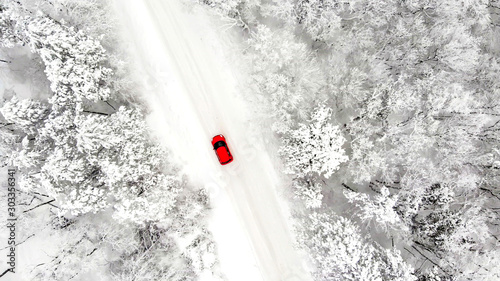 red car driving on an iced snow road, drone aerial view © tronixAS