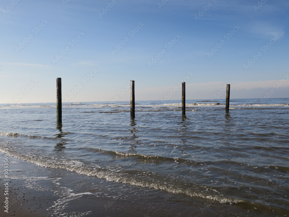 four wooden poles at the beach in the Northsea Zandvoort, The Netherlands