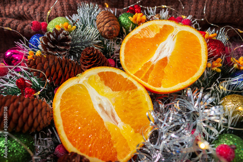 Fototapeta Naklejka Na Ścianę i Meble -  Sliced citrus orange on New Year decorations. Christmas concept. Cones, holiday lights and candies