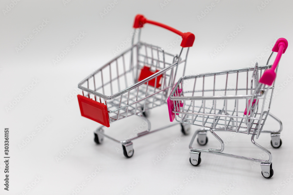 Tax letter on wooden block with coins stack, shopping cart and home model on white background.