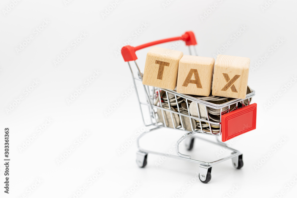Tax letter on wooden block with coins stack, shopping cart and home model on white background.