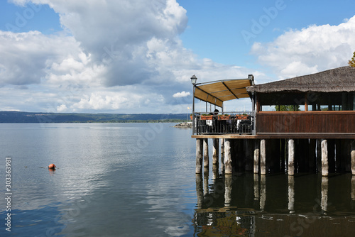 View of Bolsena Lake. A typical restaurant on wooden pilework in the background. Bolsena, Lazio, Italy
