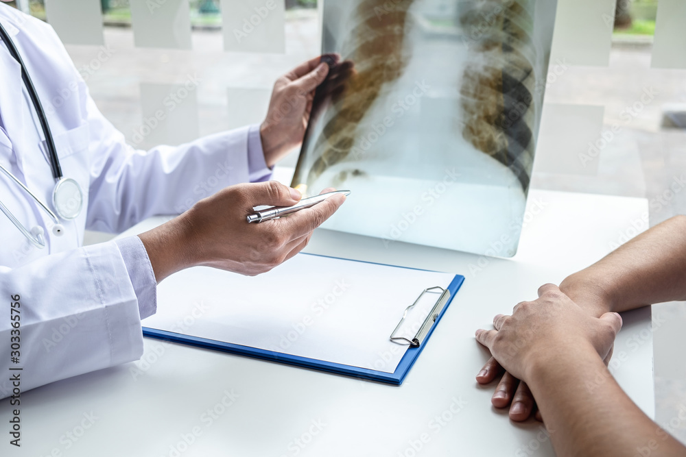 Φωτογραφία Doctor holding and looking at x-ray film examining at lungs radiograph of patien