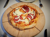 Selbstgemachte Pizza auf Holzbrett mit Salami und Pilzen lecker