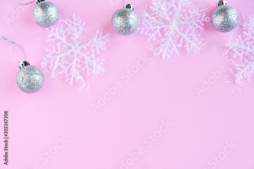 New Year 2020 flat lay with fluffy white snowflakes and silver sparkle decorative ball on pink neutral background  selective focus. Christmas and New Year flat lay shiny decorations on pink backdrop 