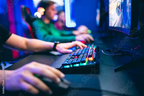 Professional cyber video gamer studio room with personal computer armchair, keyboard for stream in neon color blur background. Soft focus photo