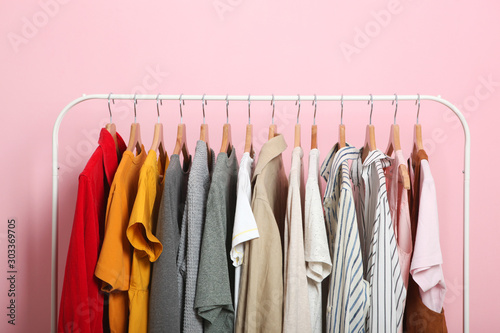 fashionable clothes on hangers on a wardrobe rack on a colored background. photo