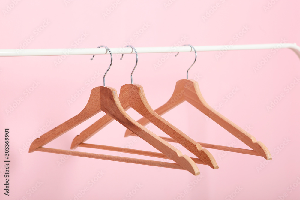 empty clothes hangers on a wardrobe rack on a colored background. - obrazy, fototapety, plakaty 