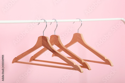 empty clothes hangers on a wardrobe rack on a colored background.