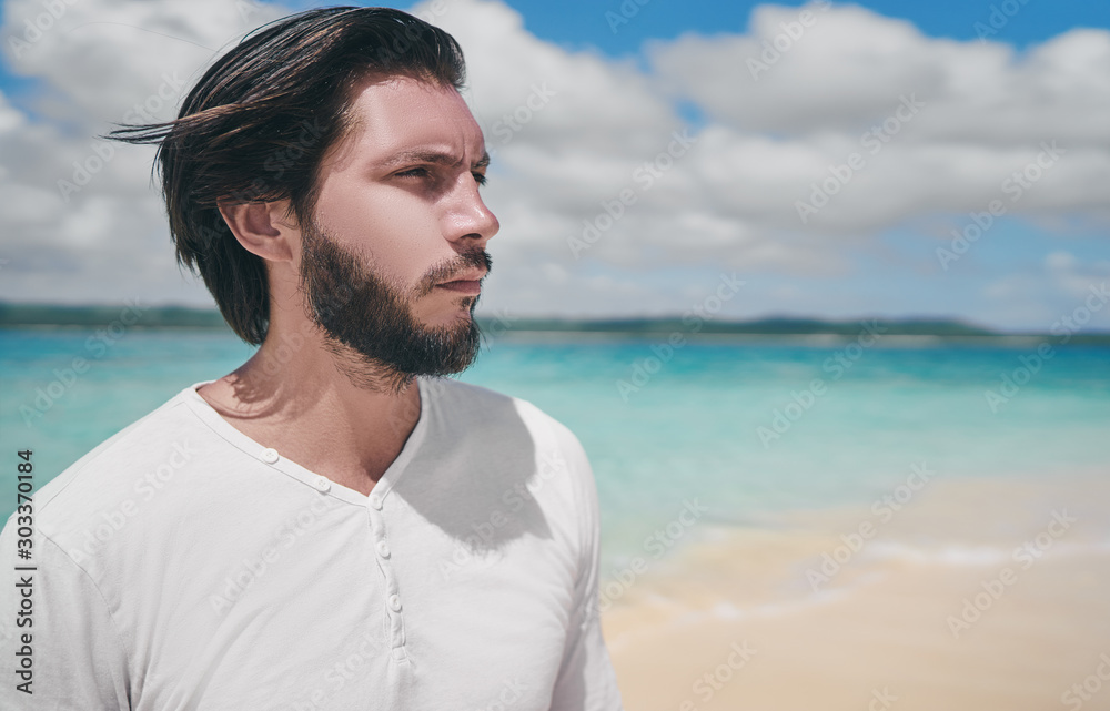 Handsome and confident. Outdoor portrait of  young bearded man on tha beach.