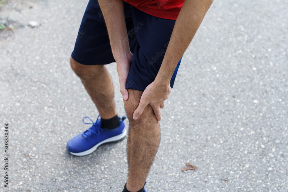 Close up of Sport man suffering with pain on sports running knee injury after running.Injury from workout concept.