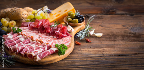 Cutting board with prosciutto, salami, ham, cheese, bread and olives