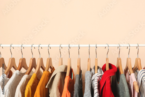 fashionable clothes on hangers on a wardrobe rack on a colored background. photo