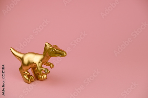 golden dinosaur statuette on pastel pink background with copy space trendy minimal art card