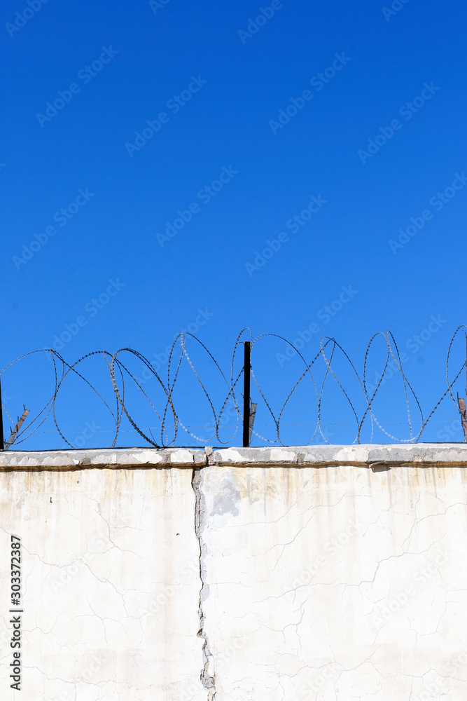 Jail wall. Highly protected prison wall with barbed wire fence Jail wall. Highly protected prison wall with barbed wire fence