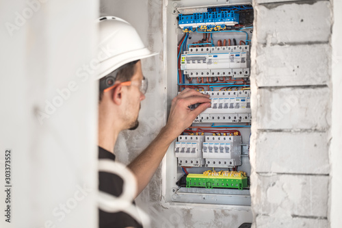 Man, an electrical technician working in a switchboard with fuses. Installation and connection of electrical equipment.