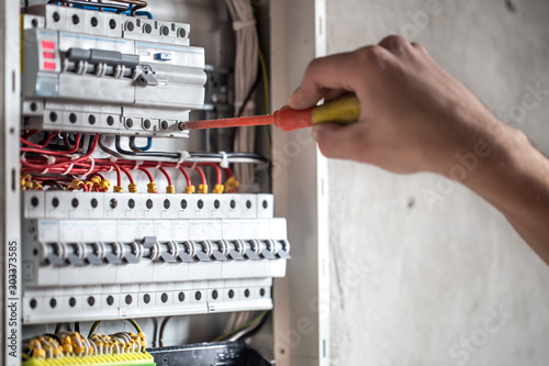 Man, an electrical technician working in a switchboard with fuses. Installation and connection of electrical equipment. Close up. photo