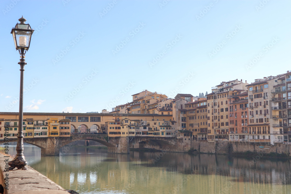 View to famous landmark ponte vecchio in florence, Italy with its reflection in the river Arno and street lamp