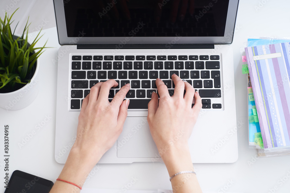 Businesswoman sitting at office desk and typing on a laptop hands close up. View from above. Businesswoman sitting at office desk and typing on a laptop hands close up. View from above.