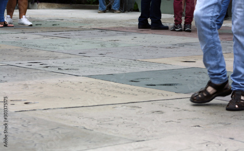Feet walking across famous handprints and footprints at Grauman's Chinese Theatre