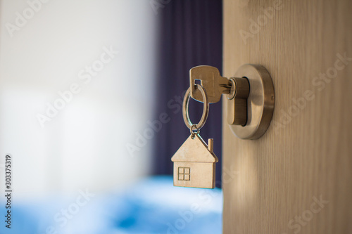 close up key on the door with morning light, personal loan concept. subject is blurry.