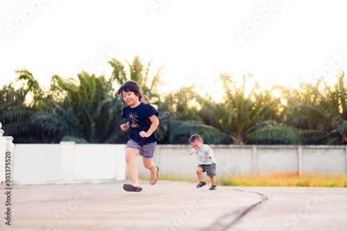 Little sister playing and running with her baby brother.Toddler kid and new sibling. Cute girl and baby boy excercise at the park in Japan.Family with children happy time. Love, trust and tenderness.