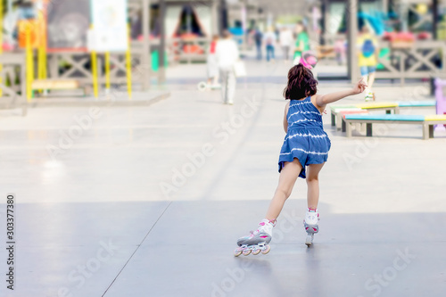little girl on roller skates in city park on summer sunny day