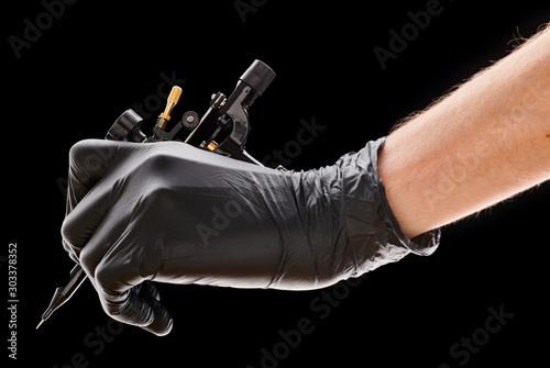Tattoo machine in artist's hand isolated on black background