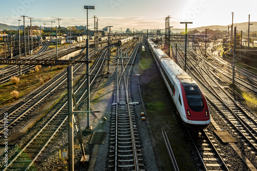 Canvas Print Modern commuter train on a European railway station at sunrise with rail tracks
