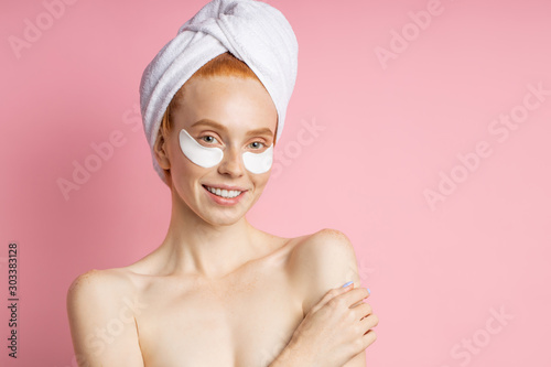 Young woman with patches under eyes isolated on pink background