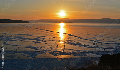Baikal Lake. Ice winter road near Olkhon Island at sunset. Winter travel on the frozen lake