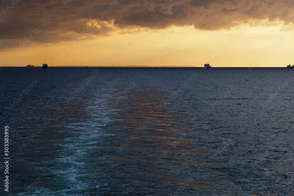 Looking on the wake of a cruise ship and beautiful sunset at horizon