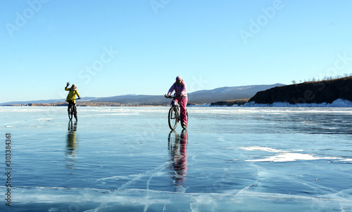 Ice biker travelers with backpacks on bike on ice of Lake Baikal. Winter sport concept. Cycling.