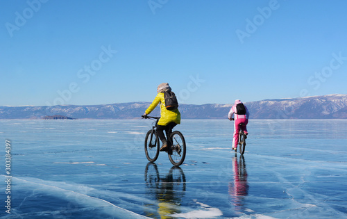 Ice biker travelers with backpacks on bike on ice of Lake Baikal. Winter sport concept. Cycling.