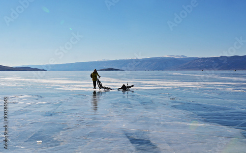 Ice biker traveler with backpacks on bike on ice of Lake Baikal. Winter sport concept. Cycling.