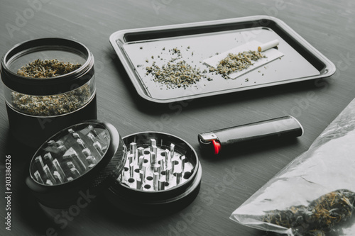 Blunt and Lighters. Hemp legalisation. Copy space. Herb grinder Fresh marihuana. Close up. CBD and THC on buds in cannabis. Cannabis buds on black wood background.