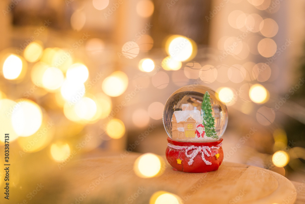 Christmas decoration, snow dome, globe with table decoration, Santaclaus on sleigh with child in winter scene, christmas tree with lights in background, selective focus