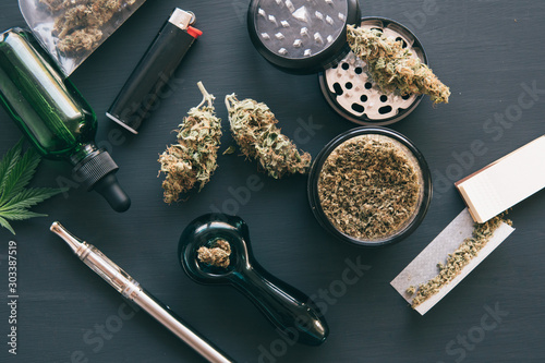 Marijuana smoking pipe CBD and THC on buds in cannabis. Macro Cannabis buds weed on black wood background. Cannabis legalisation. Top view