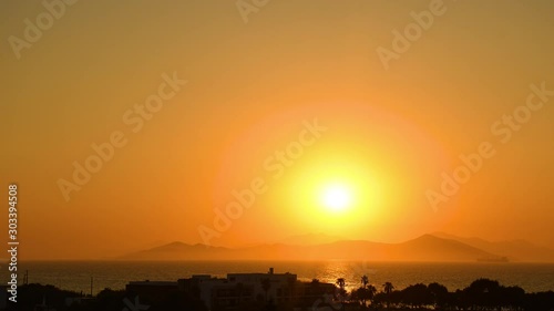 Timelapse of beautiful colorful sunset seen from the island surrounded with sea over the high mainland hills