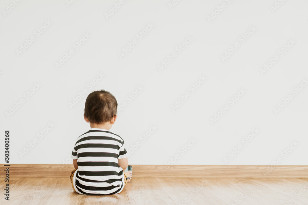 Back view of Little baby boy sitting alone and watching smartphone. - obrazy, fototapety, plakaty 