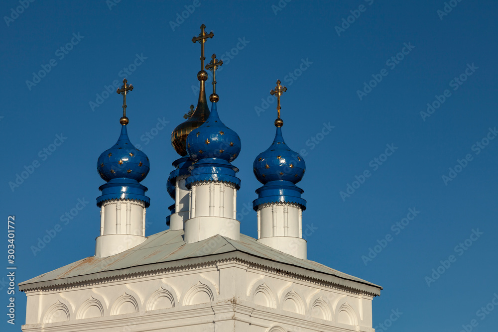Blue and gold domes of an old Orthodox church against a blue cloudless sky