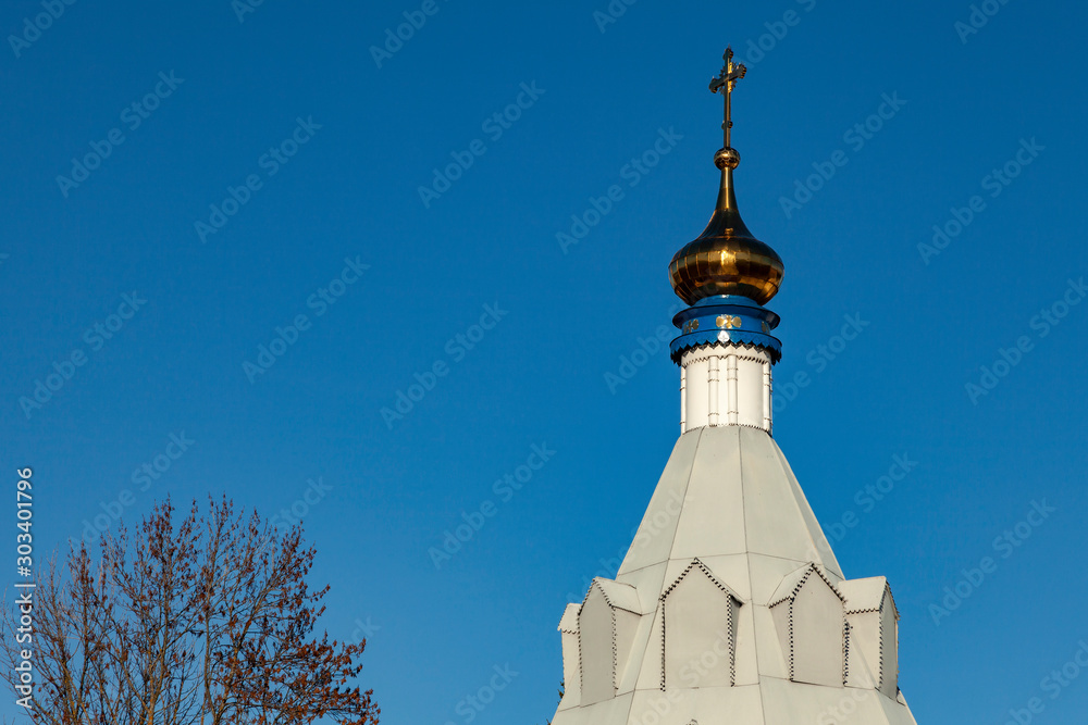 The bell tower of an old Orthodox church on a background of blue cloudless sky