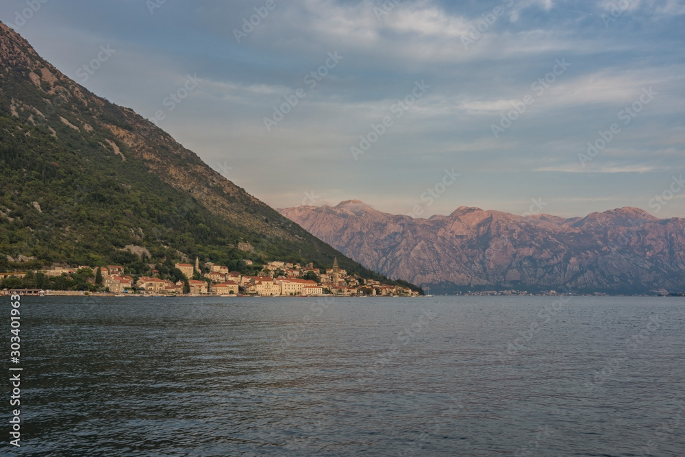 View of the ancient town of Perast (Montenegro) shortly after sunset. The bell tower of St. Nicholas Church in the distance. Bay of Kotor in early autumn. Cityscape, background.