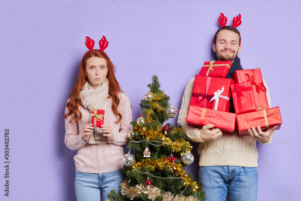 Pretty red head woman with long straight hair and freckles, holding small christmas gift with disappointed expression, looking at camera with upset face, dissatisfied with Christmas present Pretty red head woman with long straight hair and freckles, holding small christmas gift with disappointed expression, looking at camera with upset face, dissatisfied with Christmas present