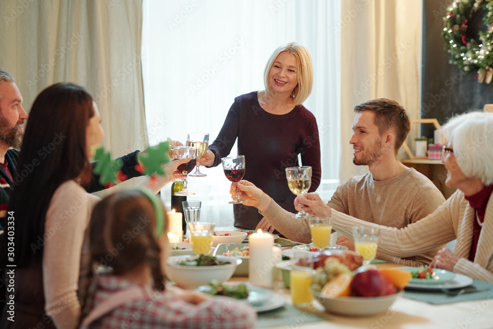 Blonde mature female and her family members clinking with glasses of wine Blonde mature female and her family members clinking with glasses of wine